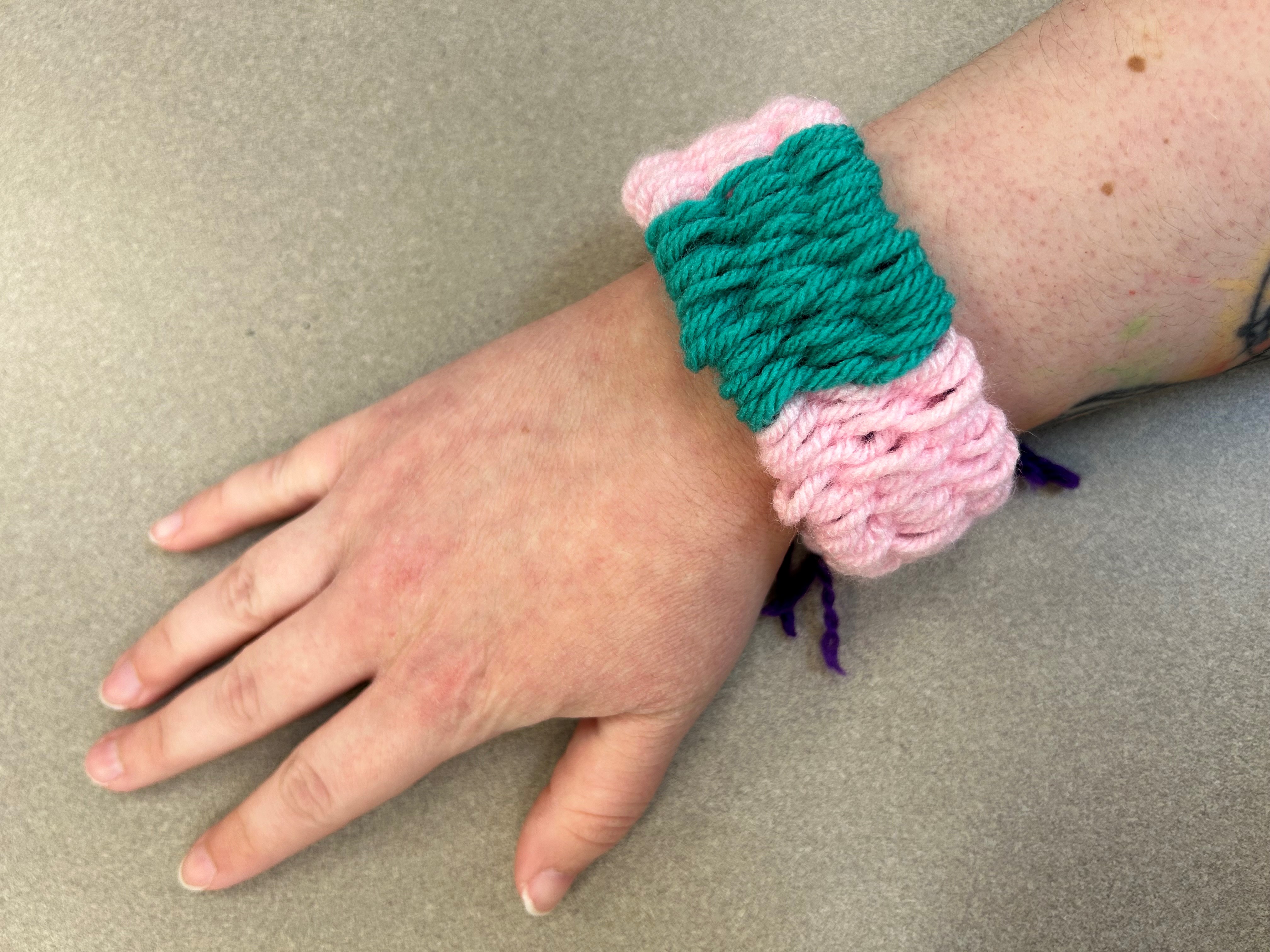 Photo of a straw-woven pink and teal bracelet on a wrist